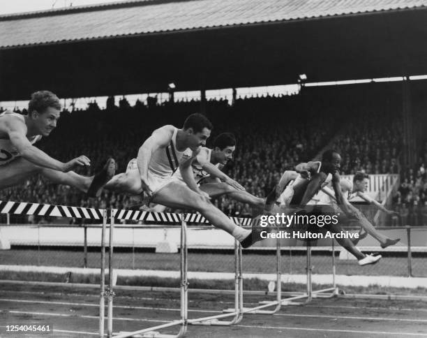 American track and field athlete Harrison Dillard taking a hurdle alongside the other competitors in the 120-yards hurdles event at the International...