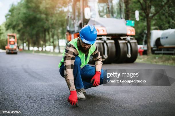 operaio edile su strada sul posto di lavoro - asphalt paver foto e immagini stock