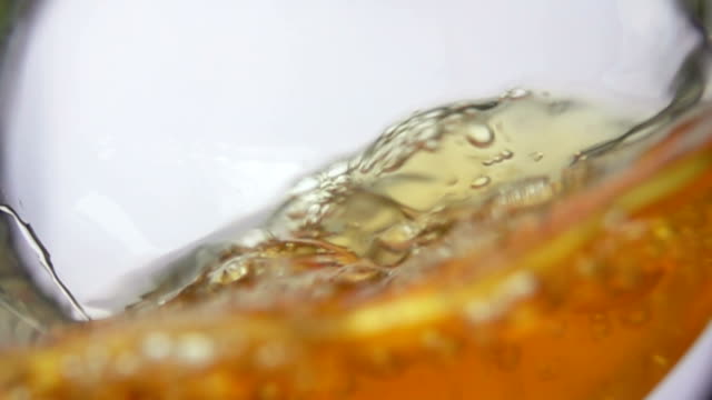 Close-up of apple juice wave pouring into the glass