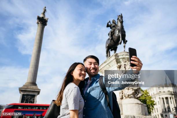 relaxed chinese tourists taking selfie in trafalgar square - tourist selfie stock pictures, royalty-free photos & images