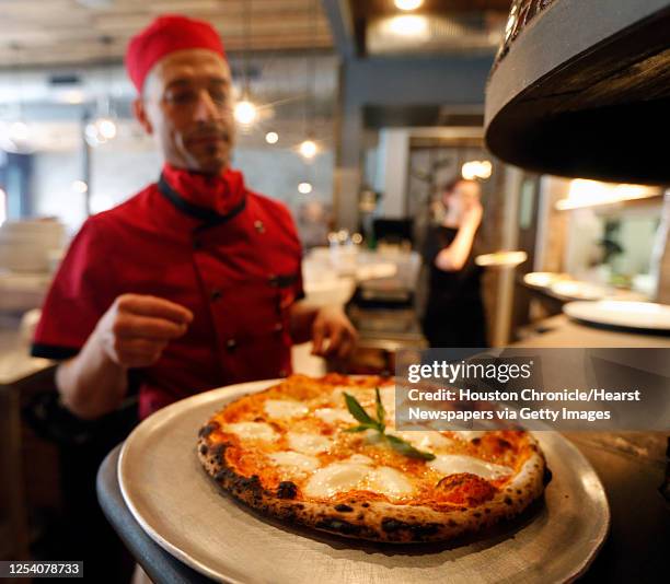 Enoteca Rossa sous chef and pizzaiolo Carlo Alberto looks over a Margherita pizza fresh out of the wood-fired oven Friday, May 13 in Houston.