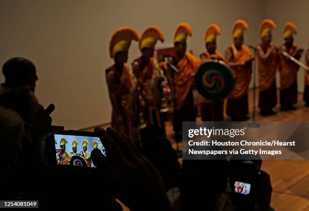 Visitor takes a photograph of Tibetan Buddhist monks from Drepung Loseling Monastery as they prepare to sweep away a mandala sand painting after...