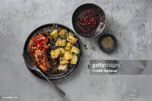 skandinavisches essen. schweinekoteletts mit wilder lingonberry-sauce und gebackenen kartoffelkeilen mit kräutern - loin stock-fotos und bilder