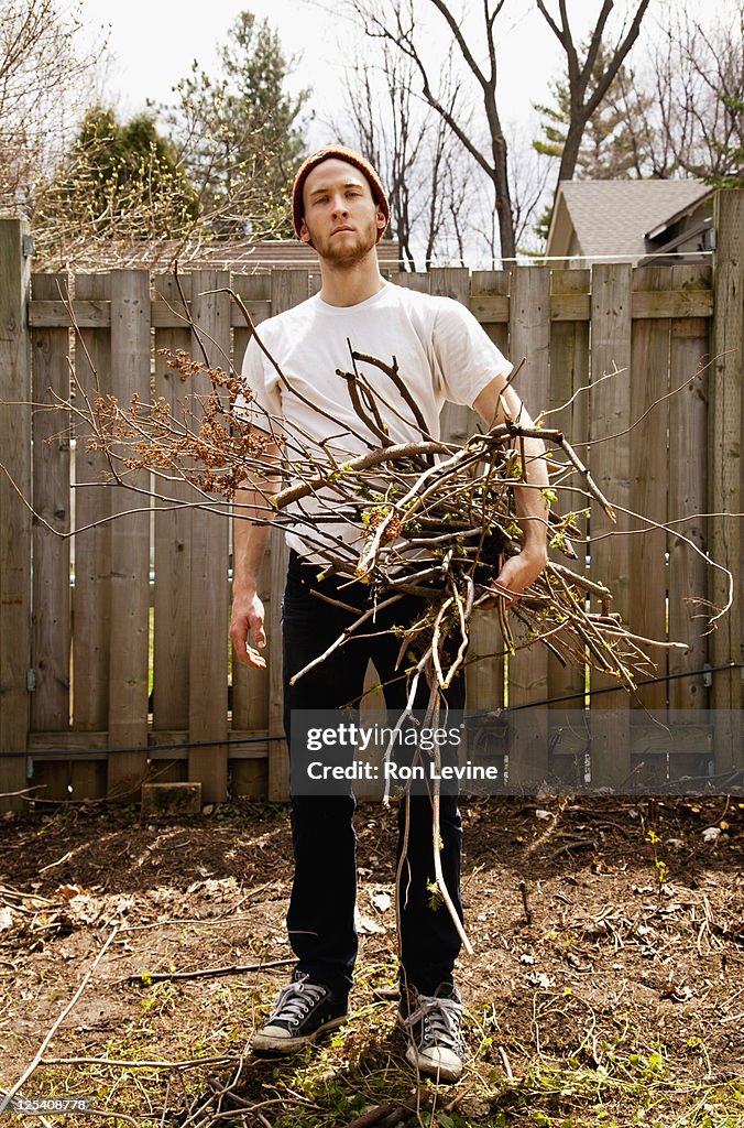 Young man with armload of branches, portrait