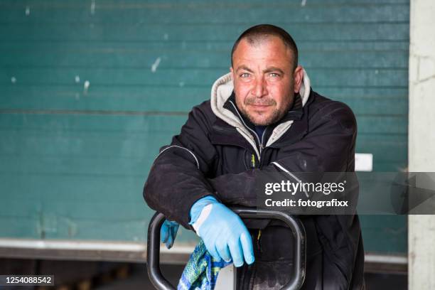 porträt eines osteuropäischen saisonarbeiters vor einem tor auf einem bauernhof - osteuropäischer abstammung stock-fotos und bilder