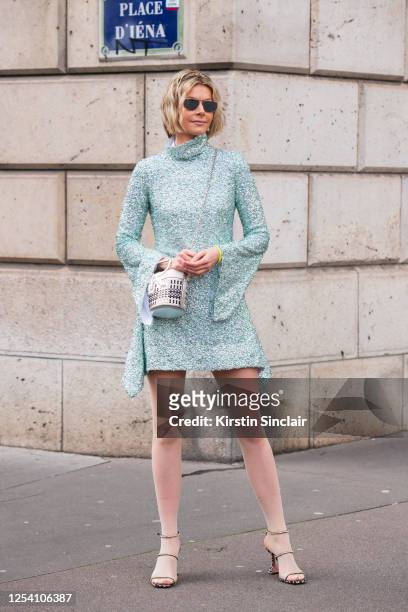 Digital influencer Kate Tik wears a Halpern Studio dress, Roger Vivier bag, Givenchy sunglasses, Falke tights and Amina Muaddi shoes on March 03,...