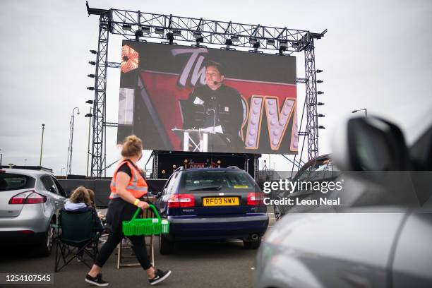 Drink delivery is made to a car as audience members watch a live comedy performance by Dom Joly at the Drive-In Club venue on July 03, 2020 in...