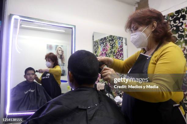 Worker cuts a client's hair with precautionary sanitary measures during the reopening of Barbershops after three months, on July 03, 2020 in Mexico...