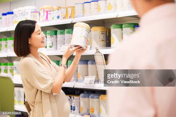 pregnant woman and her husband to buy milk powder - mom buying milk photos et images de collection