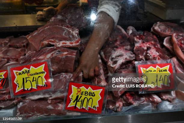 Man arranges a price sign in a butcher shop at the Central Market in Buenos Aires, on May 12, 2023. Argentina's National Institute of Statistics and...