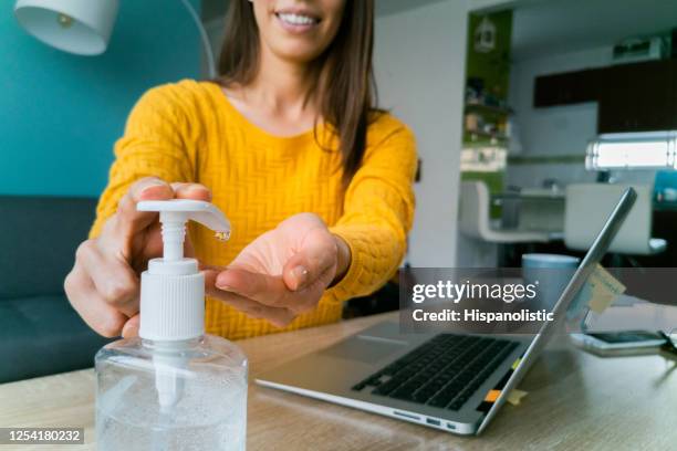 primer plano de una mujer en casa usando gel antibacteriano para desinfectar sus manos - antiséptico fotografías e imágenes de stock