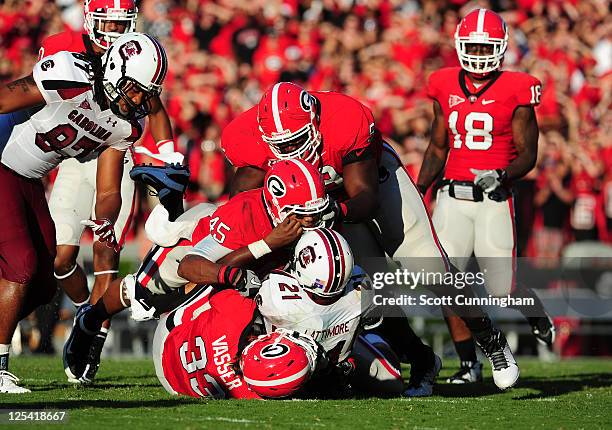 Marcus Lattimore of the South Carolina Gamecocks is tackled by Chase Vasser, DeAngelo Tyson, and Christian Robinson of the Georgia Bulldogs at...