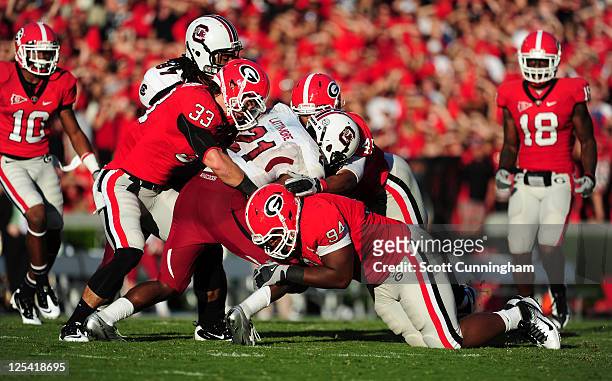 Marcus Lattimore of the South Carolina Gamecocks is tackled by Chase Vasser, DeAngelo Tyson, and Christian Robinson of the Georgia Bulldogs at...