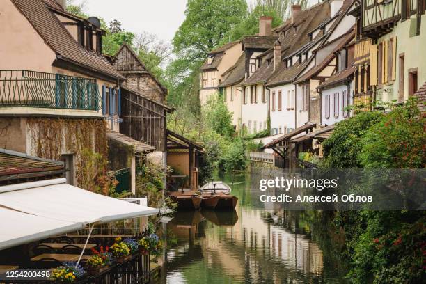 traditional french houses and old boats on the side of river lauch in petite venise, colmar, france - timber deck stock-fotos und bilder