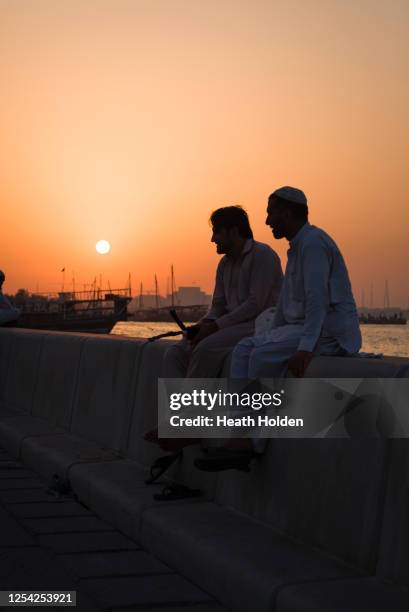 vibrant sunset with dhows along the doha corniche. - dhow qatar stock pictures, royalty-free photos & images