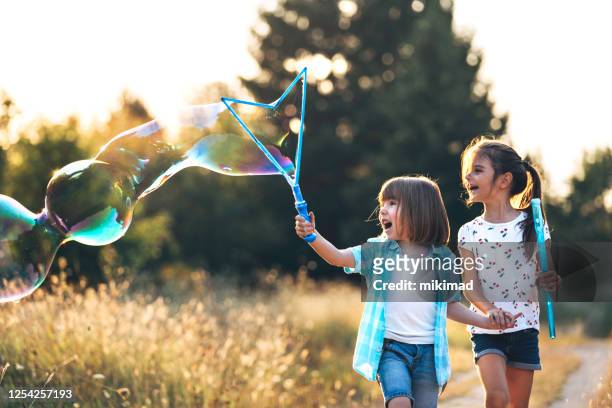happy kids plezier hebben met zeepbellen in de natuur. lopende jonge geitjes - bubbles happy stockfoto's en -beelden