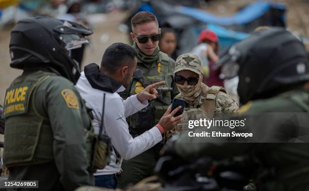 Border Patrol agents talk to migrants who have been stuck between the Tijuana-San Diego border as they hope to reach the United States on May 12,...
