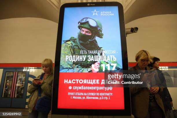 Passengers walk past a billboard, advertising contract service in the army, at the subway station, on May 12, 2023 in Moscow, Russia.The Russian...