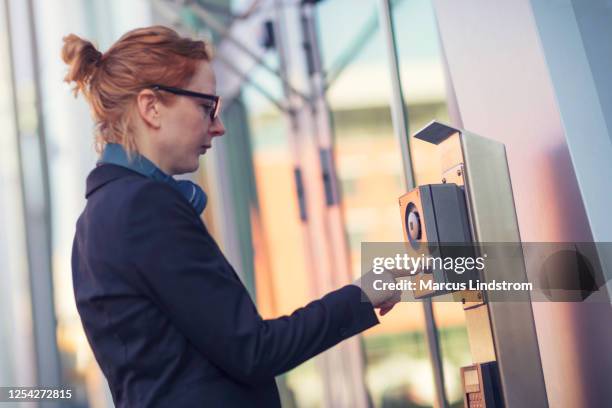 woman using an intercom at an entrance - intercom stock pictures, royalty-free photos & images