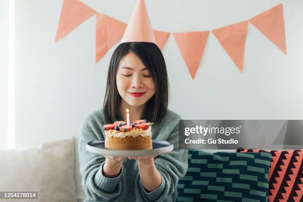 young woman celebrating birthday with a birthday cake - holding birthday cake stock pictures, royalty-free photos & images