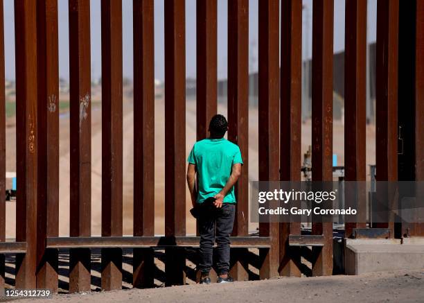 An immigrant admires the border wall while waiting to turn himselft over to U.S Border Patrol agents along the U.S.-Mexico border on Thursday, May...