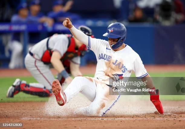 Whit Merrifield of the Toronto Blue Jays scores a run on a single by George Springer in the fifth inning against the Atlanta Braves at Rogers Centre...