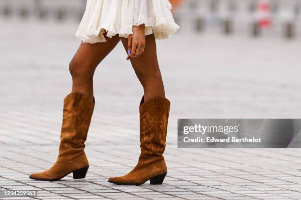 Passerby wears brown suede high cow-boy pointy boots, on July 04, 2020 in Paris, France.