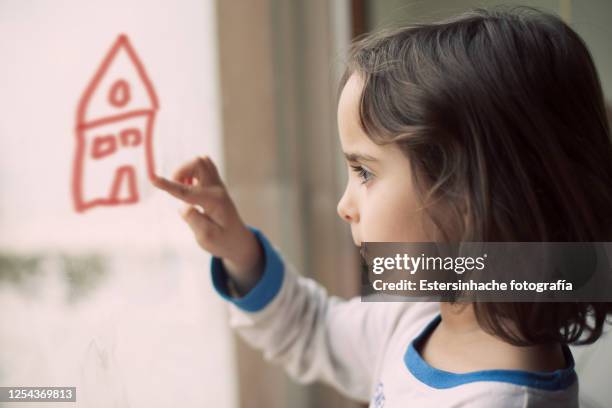 photograph of a girl drawing a house with her finger on a glass - home sweet home stockfoto's en -beelden