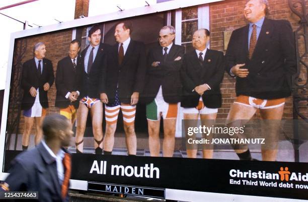 Passerby looks at a street-side billboard poster depicting the G-7 finance ministers standing in their underpants in their national colors 17...