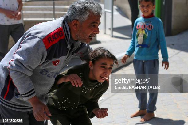 Child reacting to an Israeli air strike is assisted by a man in Beit Hanun in the northern Gaza Strip on May 13, 2023. Israeli air strikes battered...