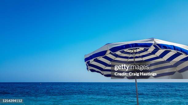 beach parasols and sunny blue skies, holiday concept, beach vacation, nice, cote d'azur, france. copy space and no people - parasol photos et images de collection