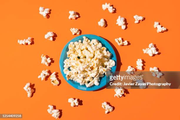 popcorn in a blue plastic plate on orange background - movie still stock-fotos und bilder