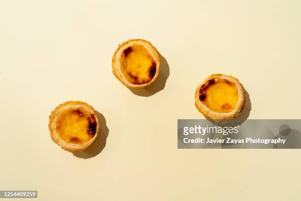 three egg tarts on yellow colored background - pastel de nata stock pictures, royalty-free photos & images