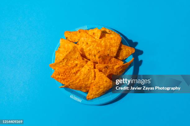 nachos on a blue colored plastic plate - nachos stockfoto's en -beelden
