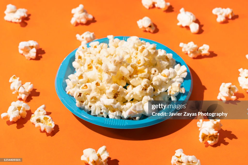 Popcorn In A Blue Plastic plate On Orange Background