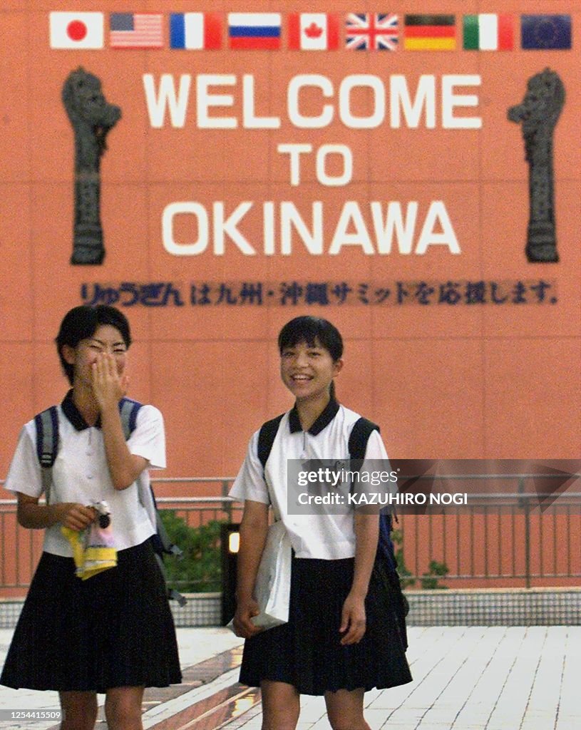 Japanese female high school students walk under a sign with
