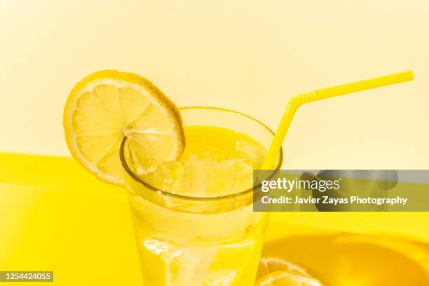 ice cold lemonade glass on yellow colored table - limonade stockfoto's en -beelden