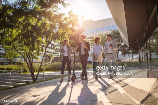 group of business people waking outside office building - four people office stock pictures, royalty-free photos & images