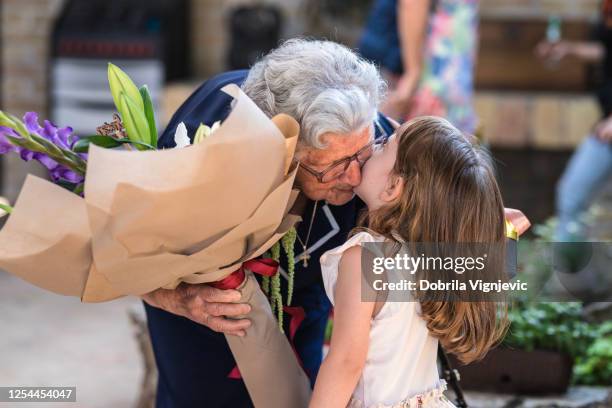 child giving grandmother bouquet of flowers and kissing her - senior woman birthday stock pictures, royalty-free photos & images