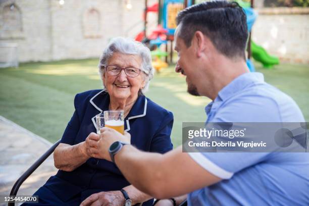 fröhliche alte dame mit getränken mit ihrem sohn - altbier stock-fotos und bilder
