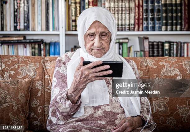 elderly middle eastern woman with smartphone - arab old woman stock-fotos und bilder