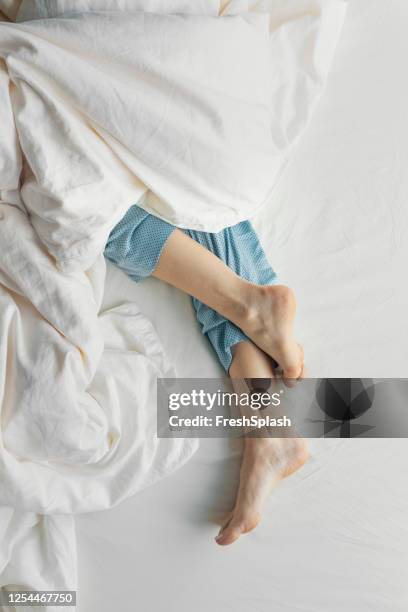 feet of a woman in blue pajamas sleeping in bed - feet in bed stock pictures, royalty-free photos & images