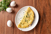 Omelet with parsley and cheese for breakfast on wooden background.