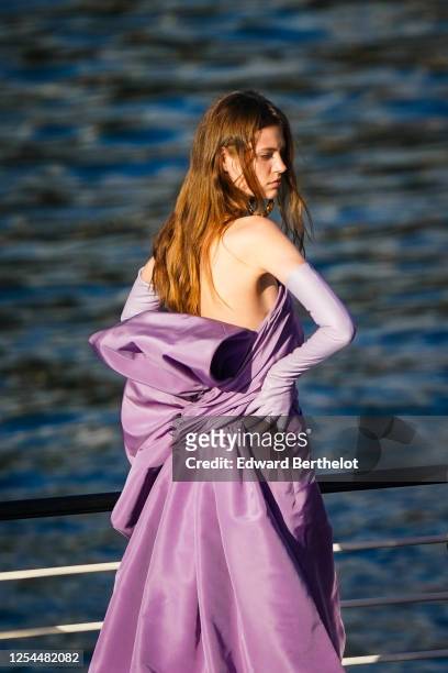 Model wears purple long gloves, a purple lustrous silky long dress, during the "Balmain Sur Seine" Performance, on a barge on the Seine river, on...