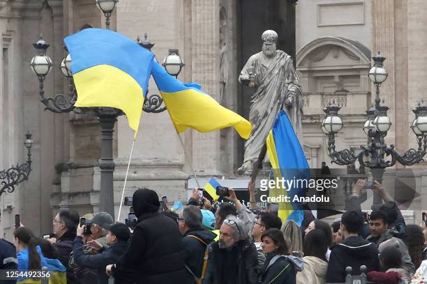 Ukrainians wave national flags in St. Peter's Square as they wait for the exit of Ukrainian President Volodymyr Zelenskyy at the end of his meeting...