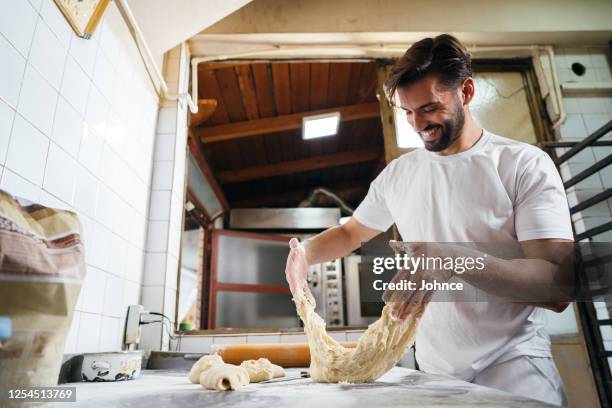 handsome baker kneading the dough - kneading stock pictures, royalty-free photos & images