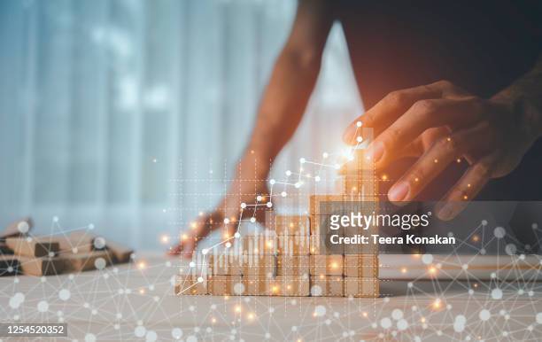 hand of a businesswoman is arranging wooden toys as steps along the rising graph.concept for business growth success process - organisatie stockfoto's en -beelden