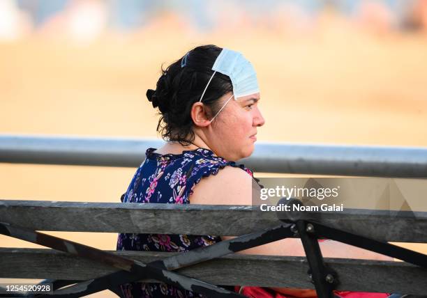 Person wears a face mask on her forehead at Brighton Beach in Coney Island as New York City moves into Phase 2 of re-opening following restrictions...