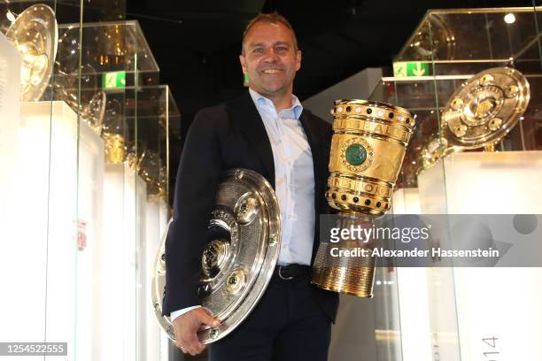 Hans-Dieter Flick, head coach of FC Bayern Muenchen hands over the DFL Championship 2020 winners trophy and DFB Cup 2020 winners trophy to the FCB...