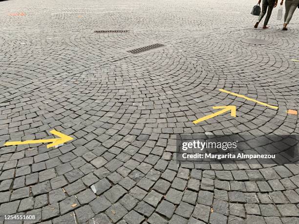 covid-19 signage with yellow arrows at the city center of lausanne - low section stock-fotos und bilder